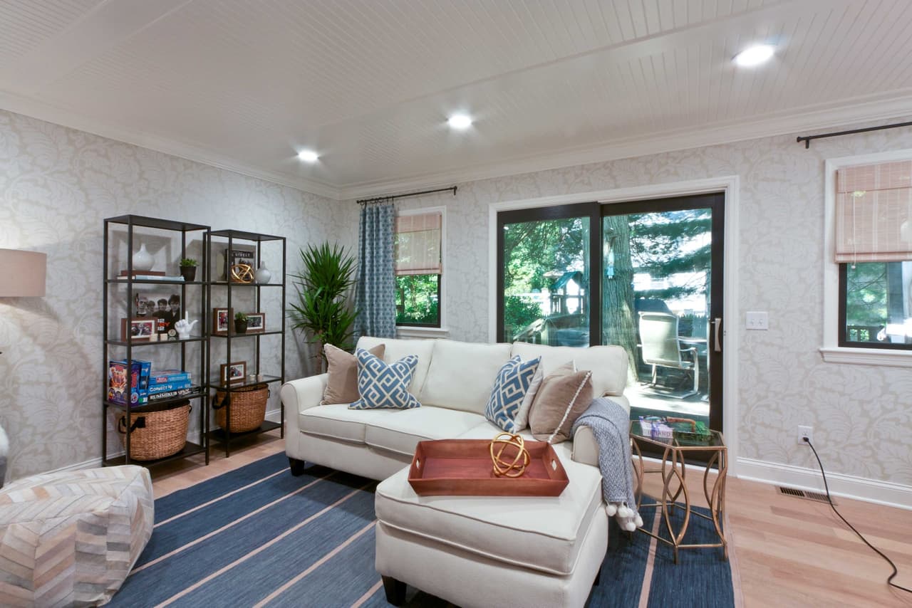Living room with a white sectional, a striped blue rug, steel-framed shelving and sliding doors to the garden