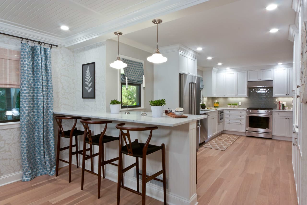 Kitchen peninsula with bentwood counter stools and dome pendants, open to the room beyond