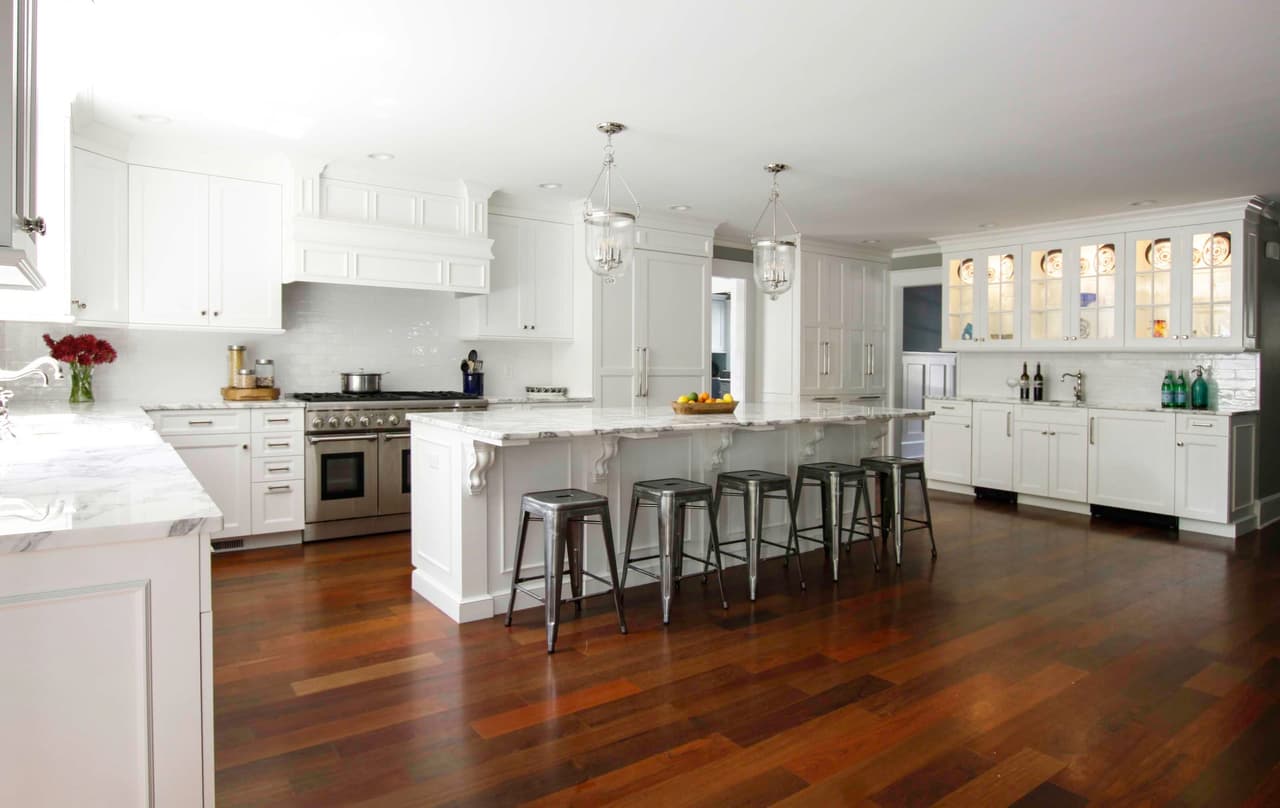 Kitchen looking down the island toward a glass-front hutch, with counter stools and a marble counter