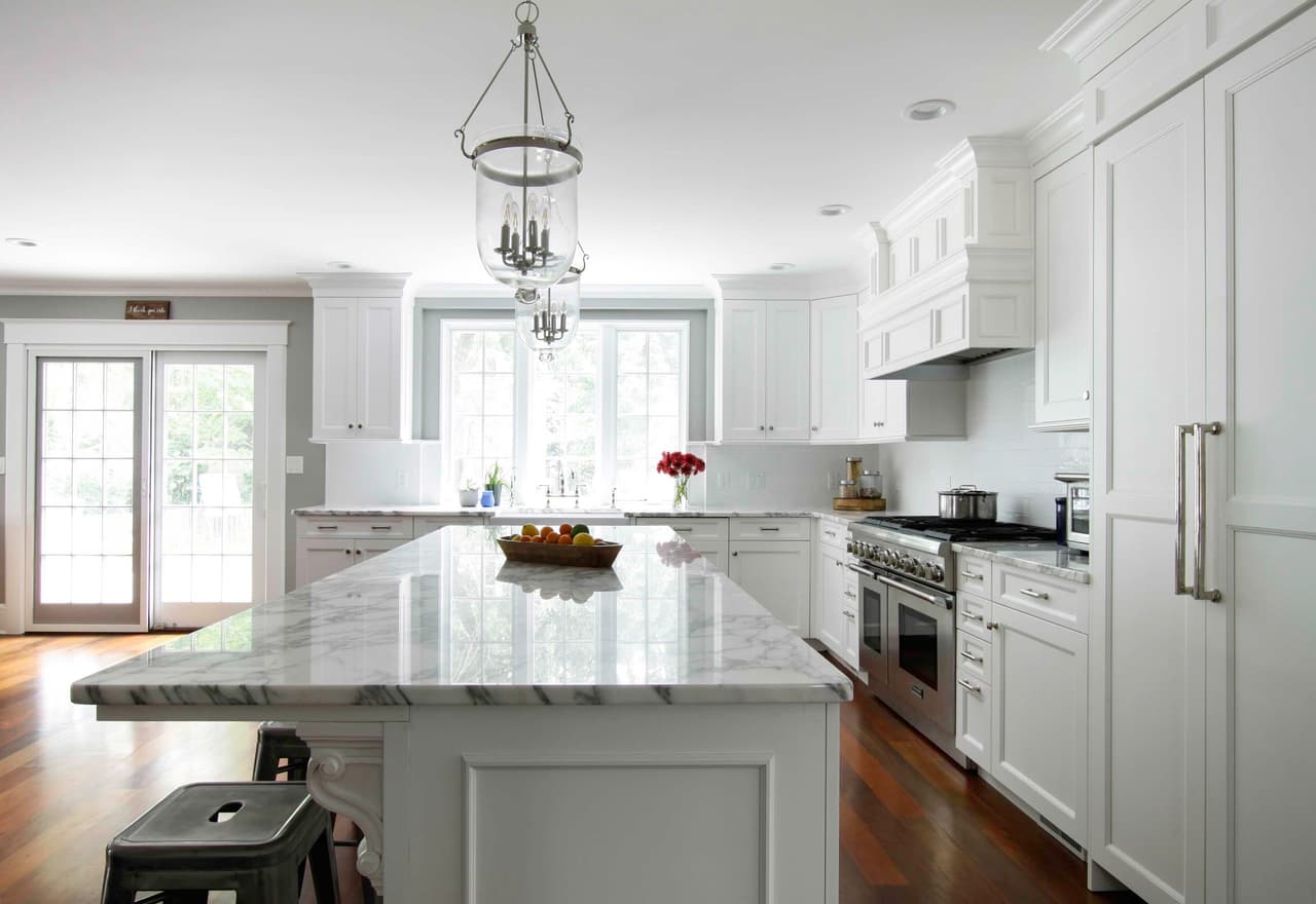 Kitchen island with a lantern chandelier above, a professional range and a door to the garden