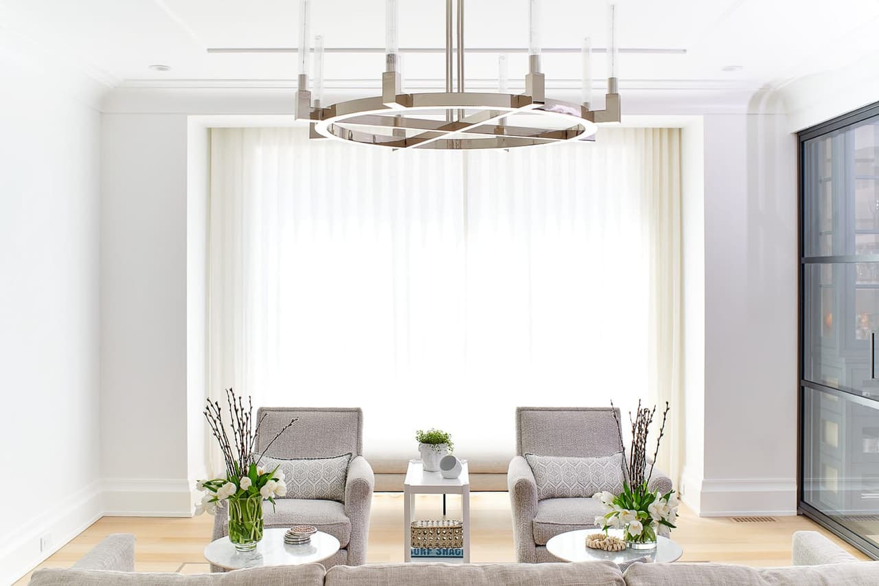 Sitting area in the Mroz family home in Westfield, NJ, with two armchairs at a sheer-curtained window under an iron ring chandelier