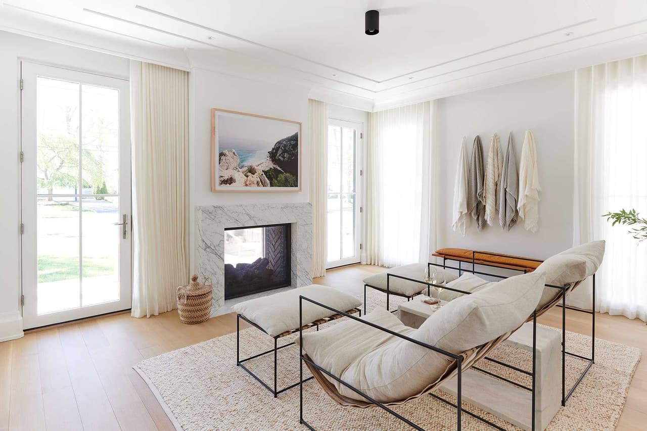 Living room with a plaster fireplace, low-slung lounge chairs on a black steel frame and white oak floors