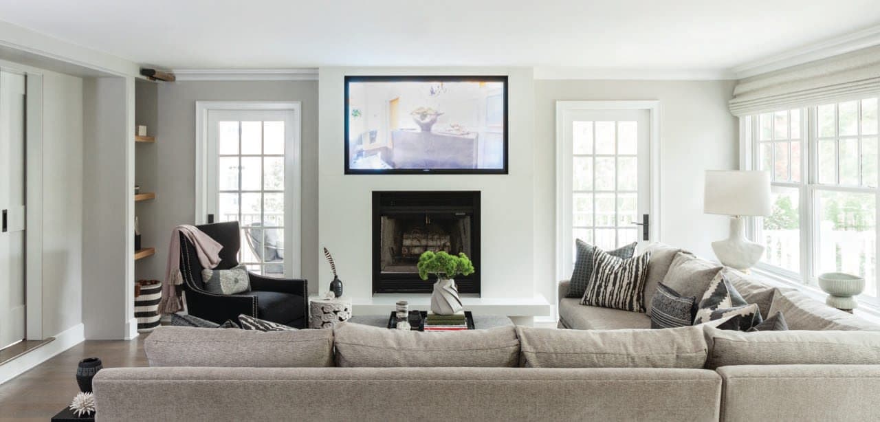 Living room with facing sofas, pale green walls and a fireplace set between windows