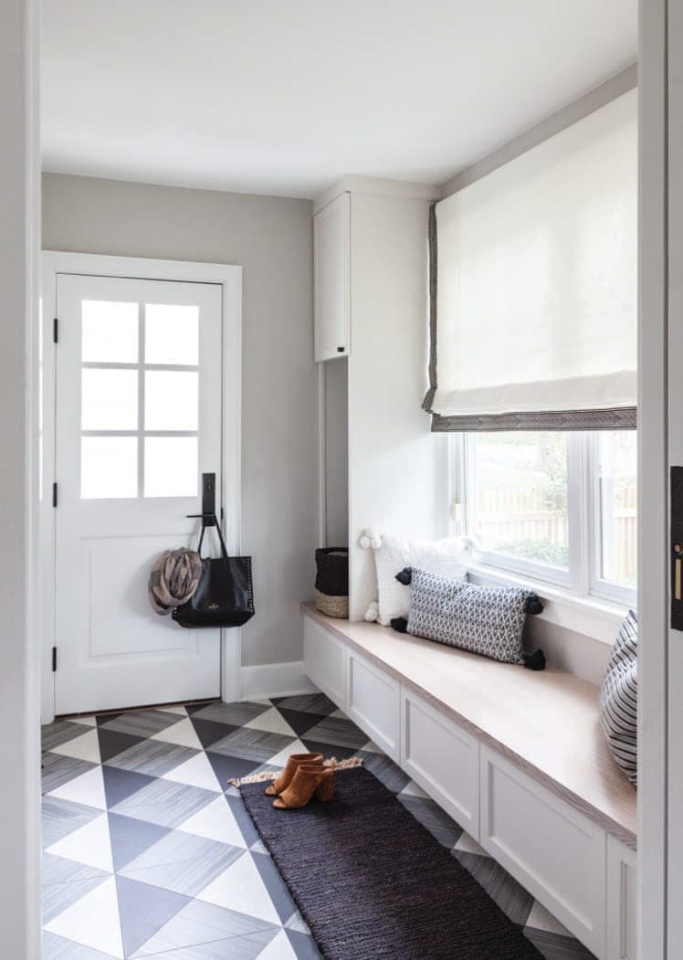 Mudroom of a Westfield, NJ home with a built-in bench under the window, hooks by the back door and a black and white diamond tile floor