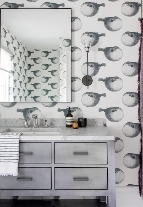 Powder room in a Westfield, NJ home papered in a large black and white print, with a gray vanity, a marble top and a round mirror