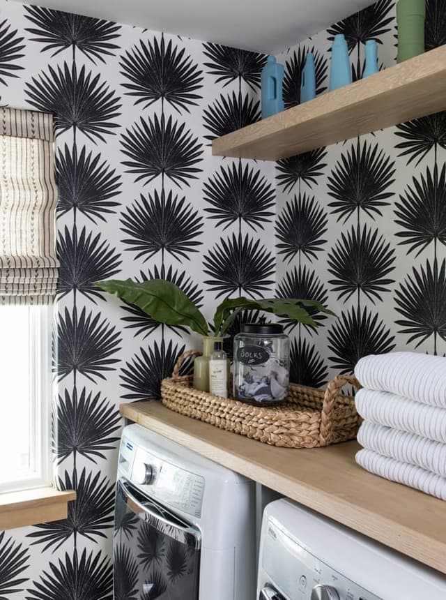 Washer and dryer under an oak counter against a black and white palm-print wall in a Westfield, NJ laundry room, with folded towels on the shelf above