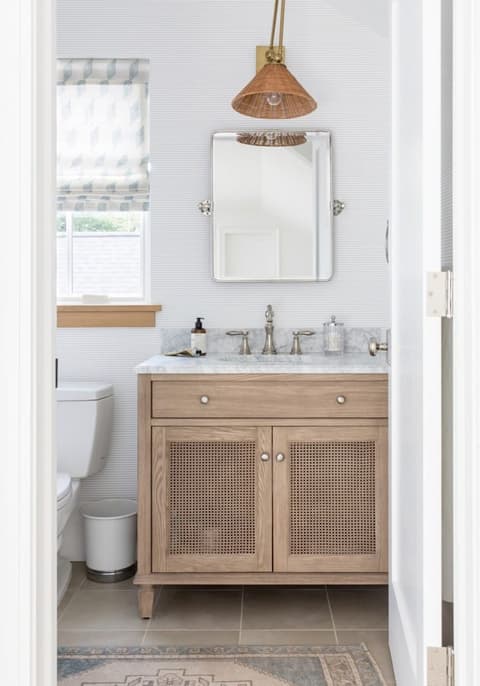 Small bathroom in a Westfield, NJ home with a cane-fronted oak washstand, a marble top and an aged brass mirror and light above
