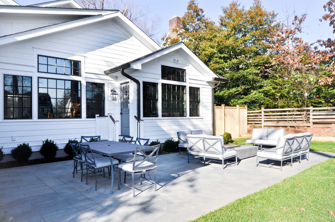 Bluestone patio with a dining set and lounge chairs beside the white clapboard rear elevation in Westfield, NJ