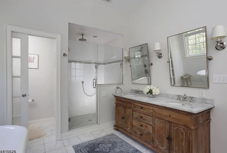 Double vanity in reclaimed wood with a stone top and pivoting mirrors in the primary bathroom of a Westfield, NJ coastal colonial renovation