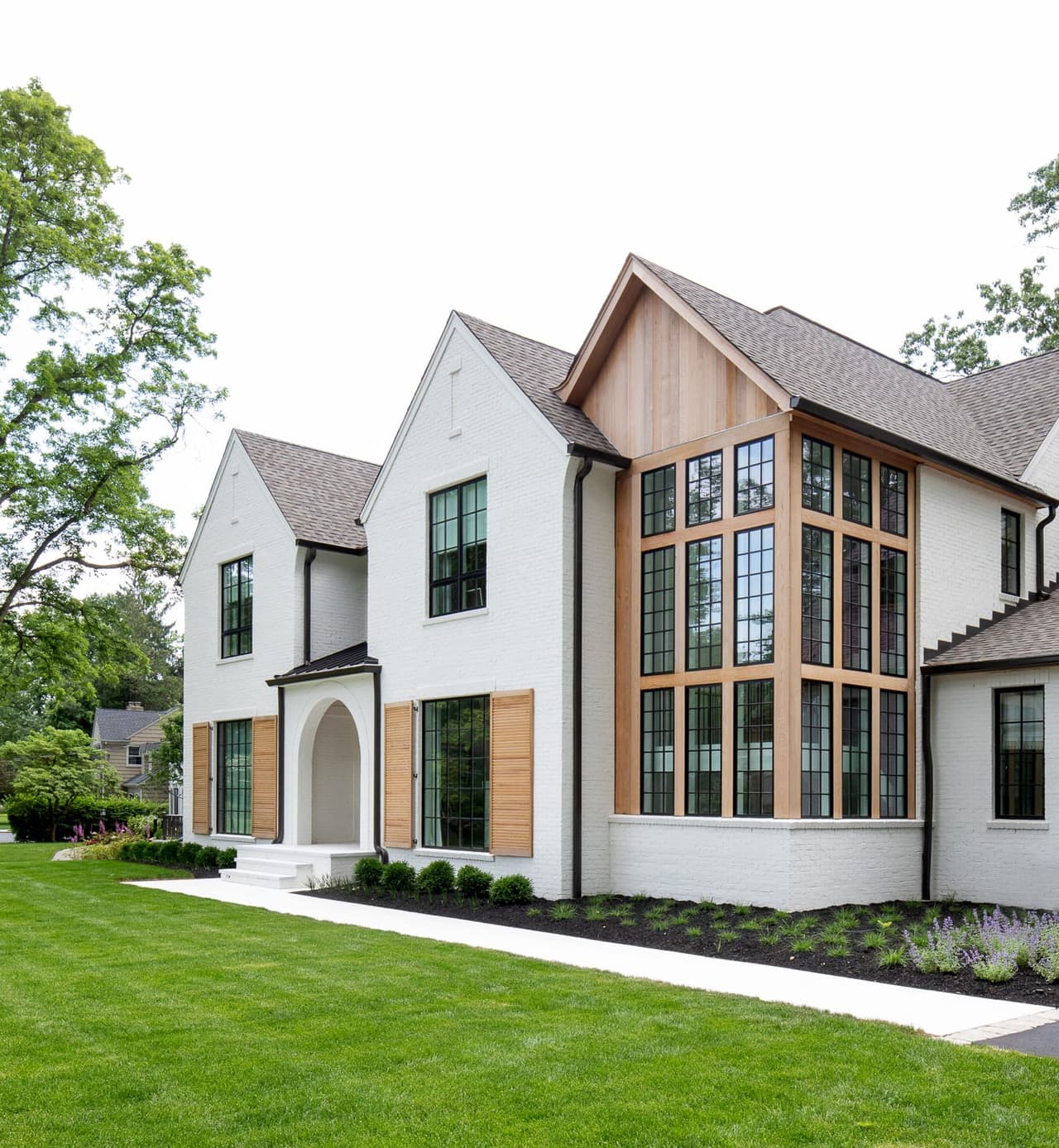Angled view of the gabled window bay and cedar shutters on a white painted brick custom home in Westfield, NJ