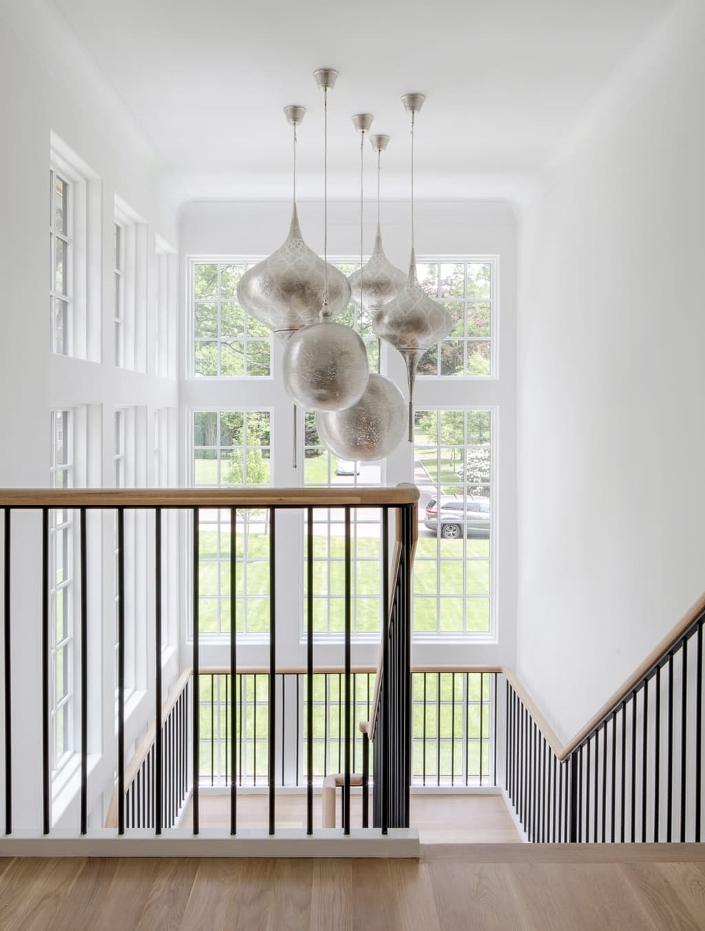 Stairwell of a Westfield, NJ custom home seen from the landing above, the alabaster pendant cluster hanging down through the open well