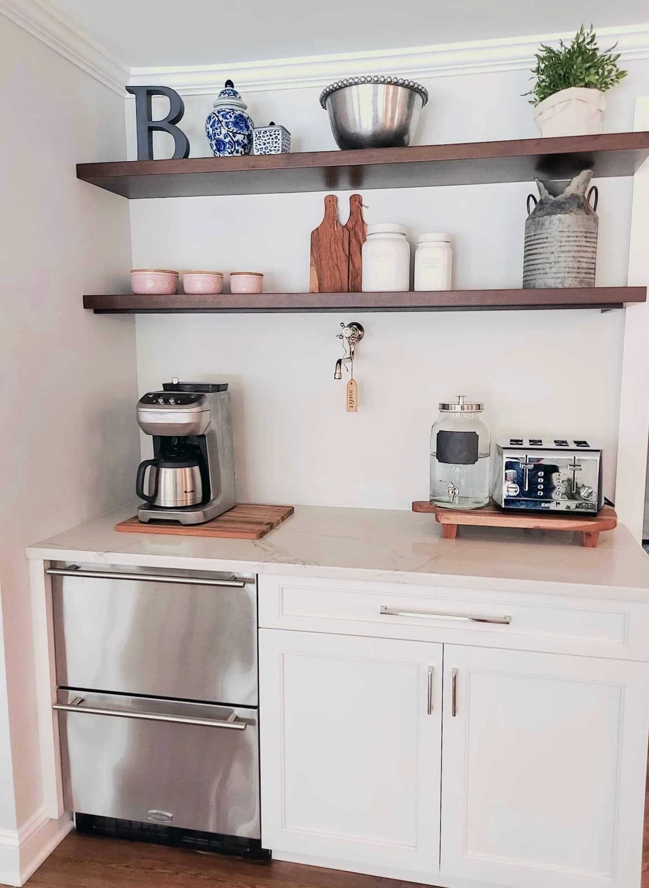 Coffee station with floating walnut shelves, a drawer refrigerator and small appliances on the counter