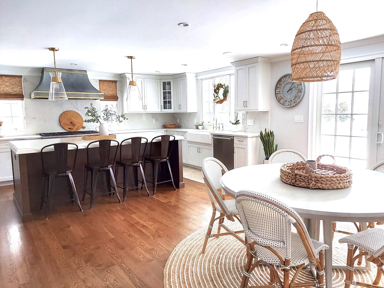 Kitchen and eat-in area with a dark island, counter stools, a plaster hood and a woven pendant over a round table