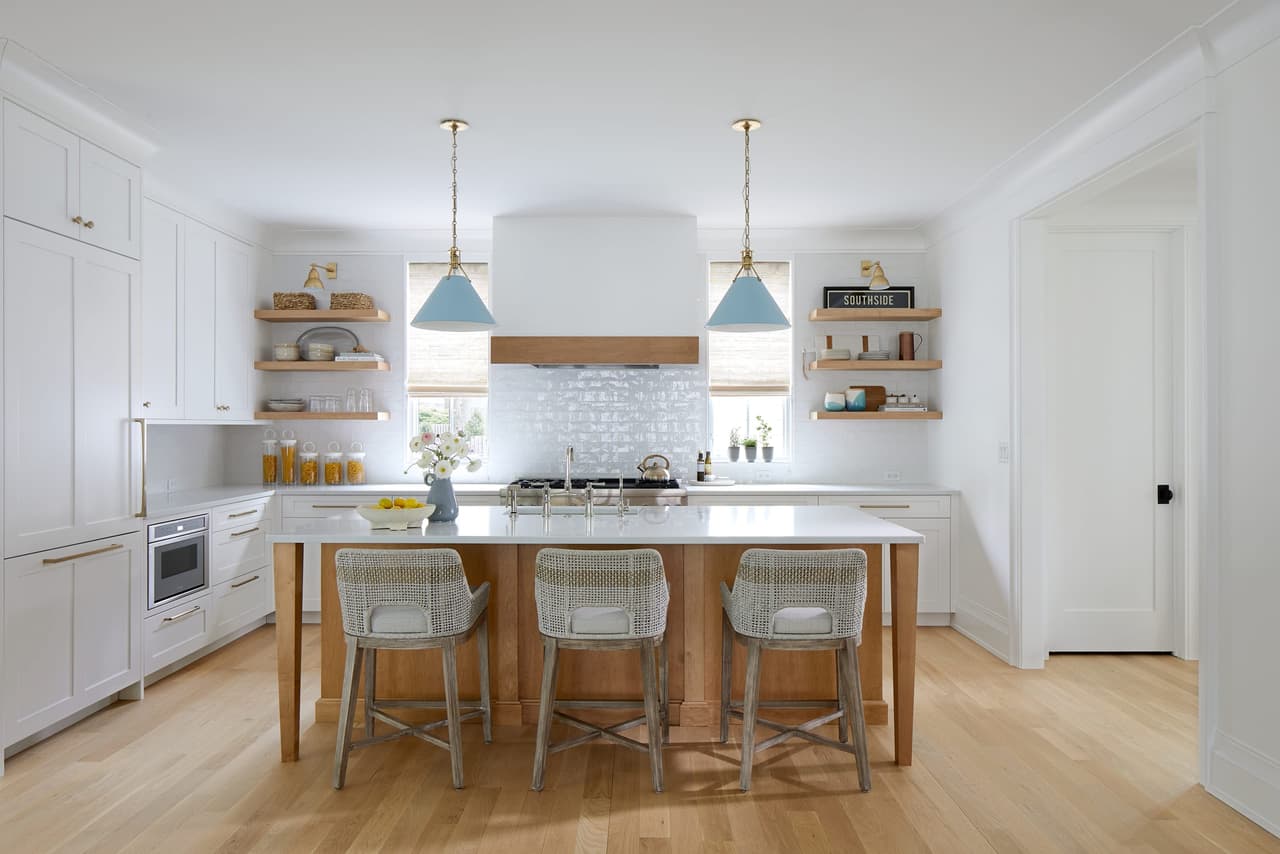 Kitchen with white cabinetry, a white oak island, open oak shelving and a pair of pale blue cone pendants