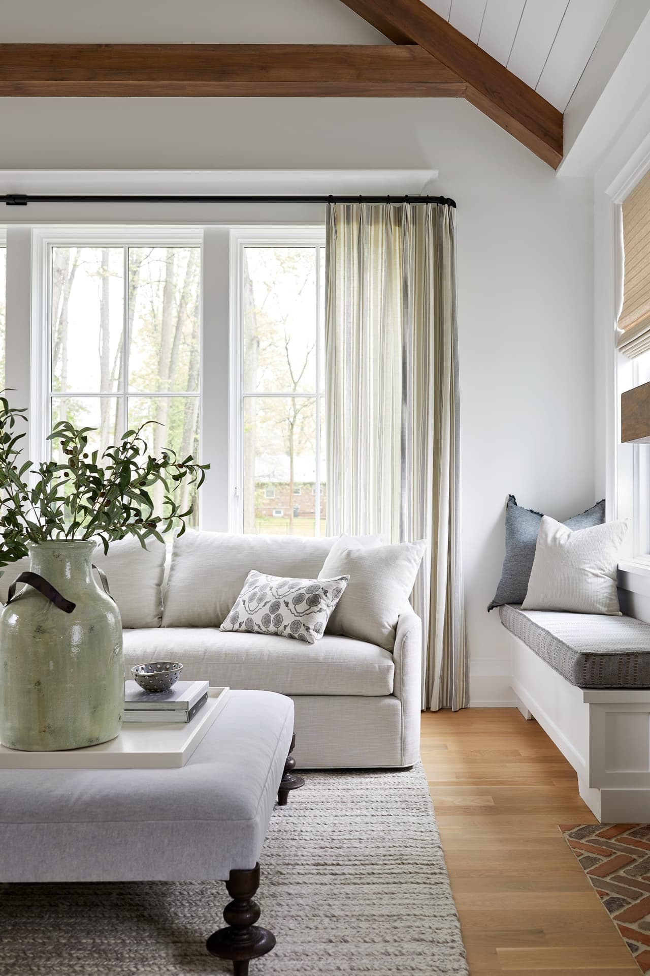 Family room detail with a built-in window-seat bench, a slipcovered sofa and an exposed stained beam overhead
