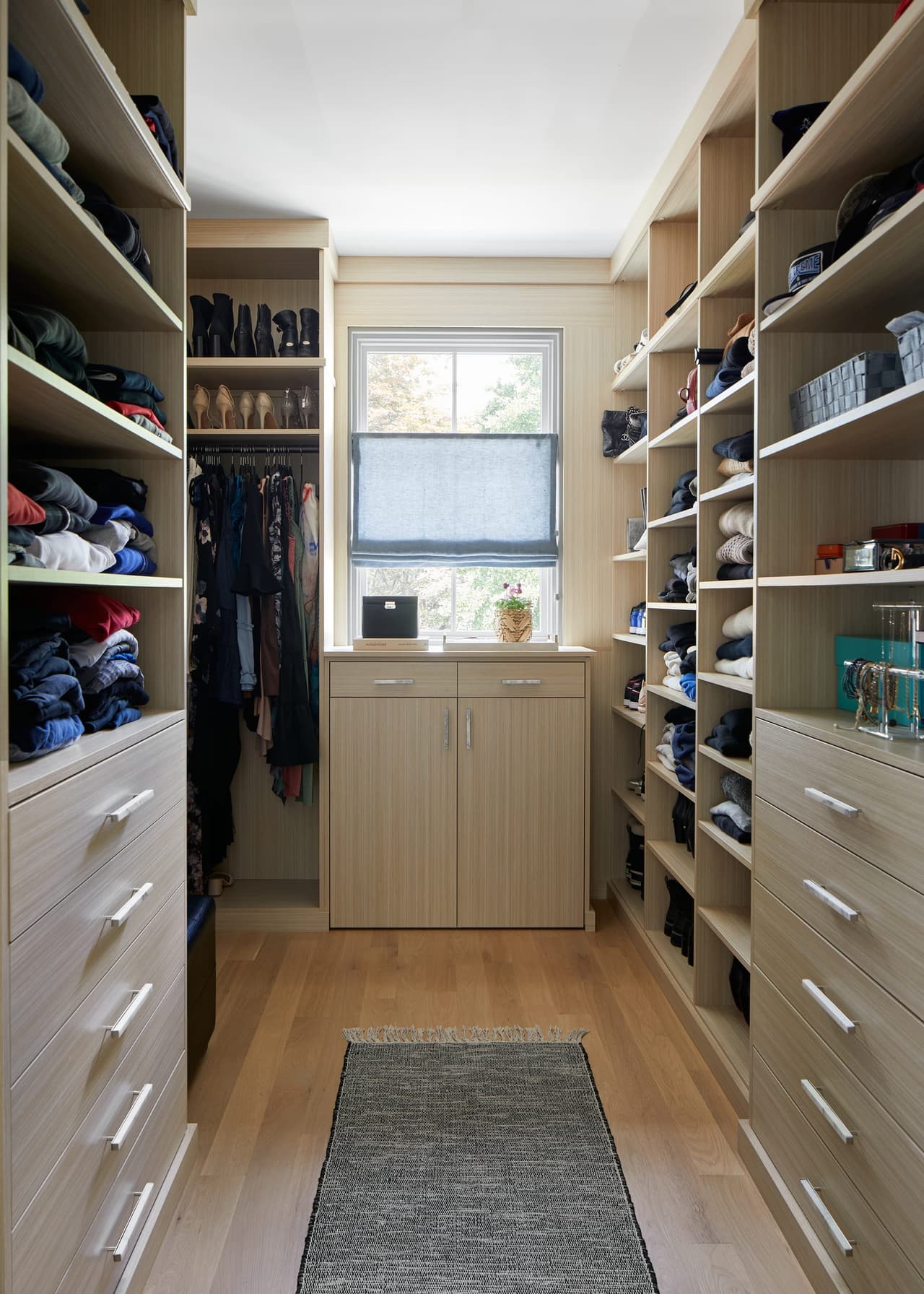 Fitted walk-in closet in a Westfield, NJ renovation and addition, with open shelving and drawers down both sides to a window at the end