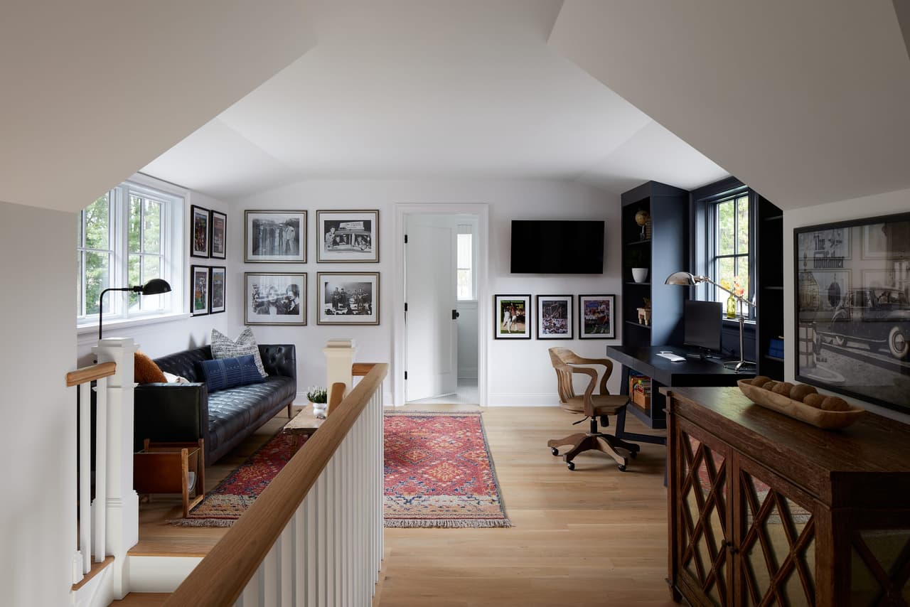 Attic office and sitting area in a Westfield, NJ custom home, with a tufted sofa, a built-in desk and a wall-mounted television under the roof slope