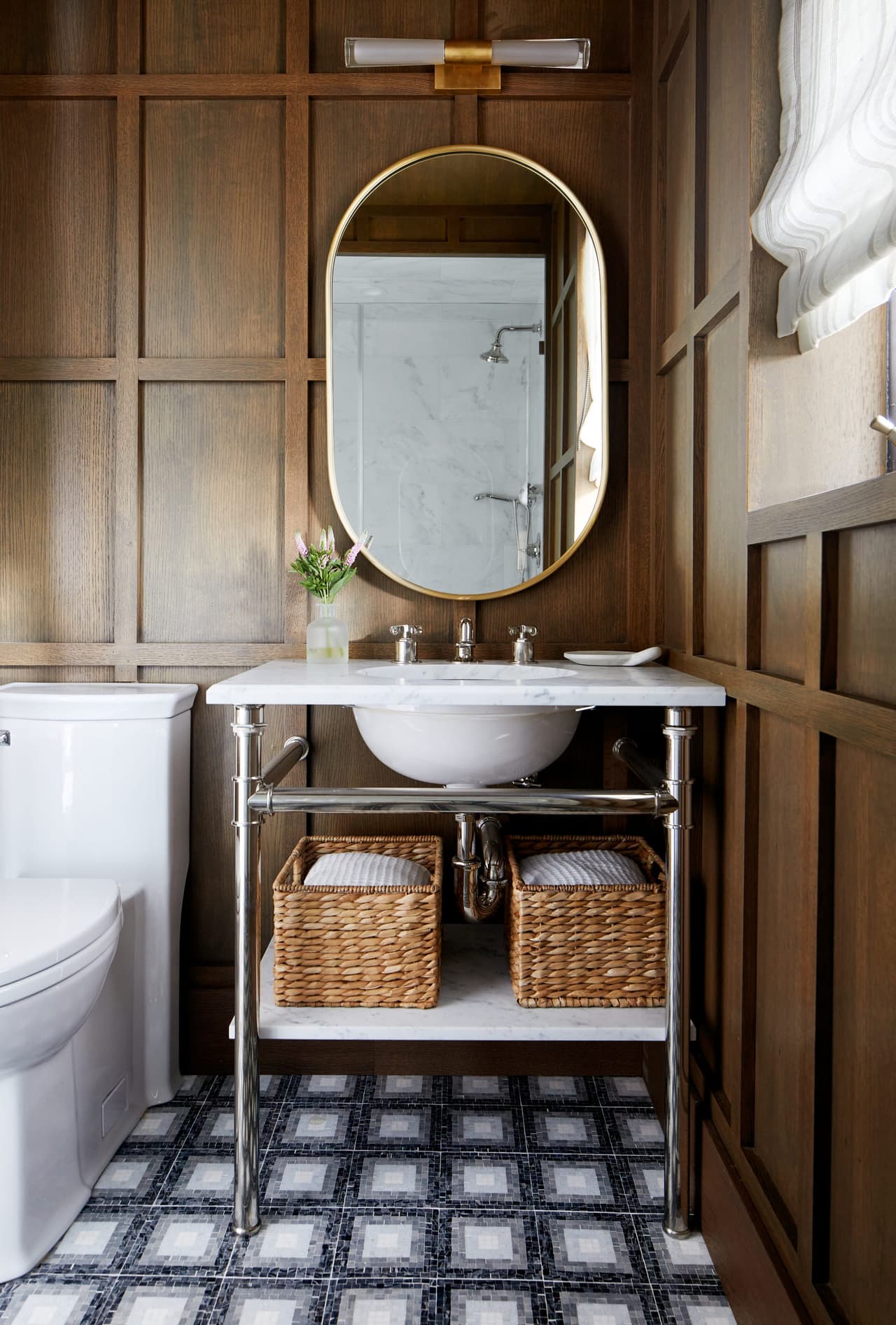 Powder room in a Westfield, NJ renovation, with wood-paneled walls, an arched mirror, a wall-mounted basin on a console and a marble mosaic floor