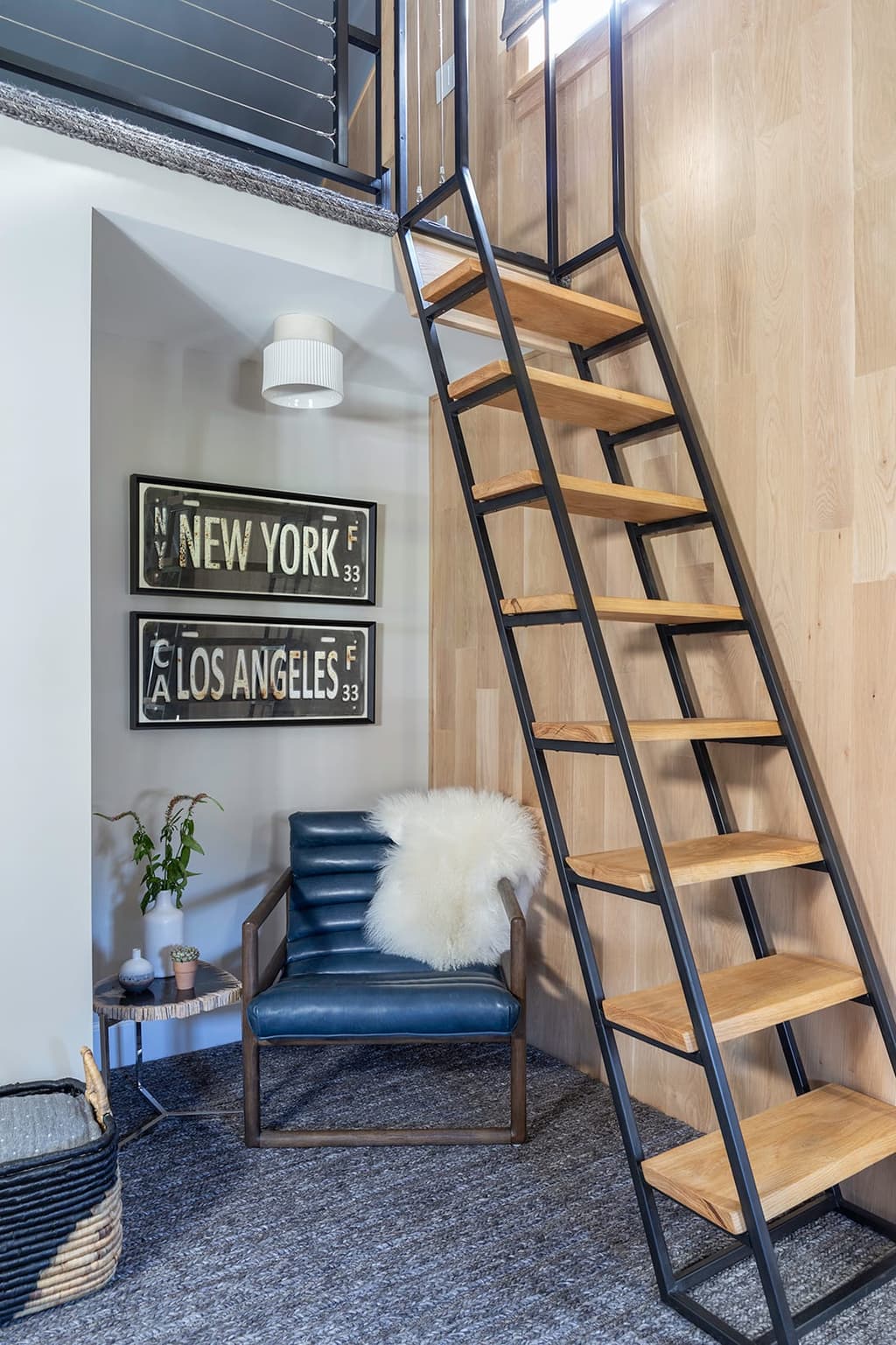 Loft bedroom in a Westfield, NJ remodel, with a black metal and oak ship's ladder up to the loft and city-name signs on the wall