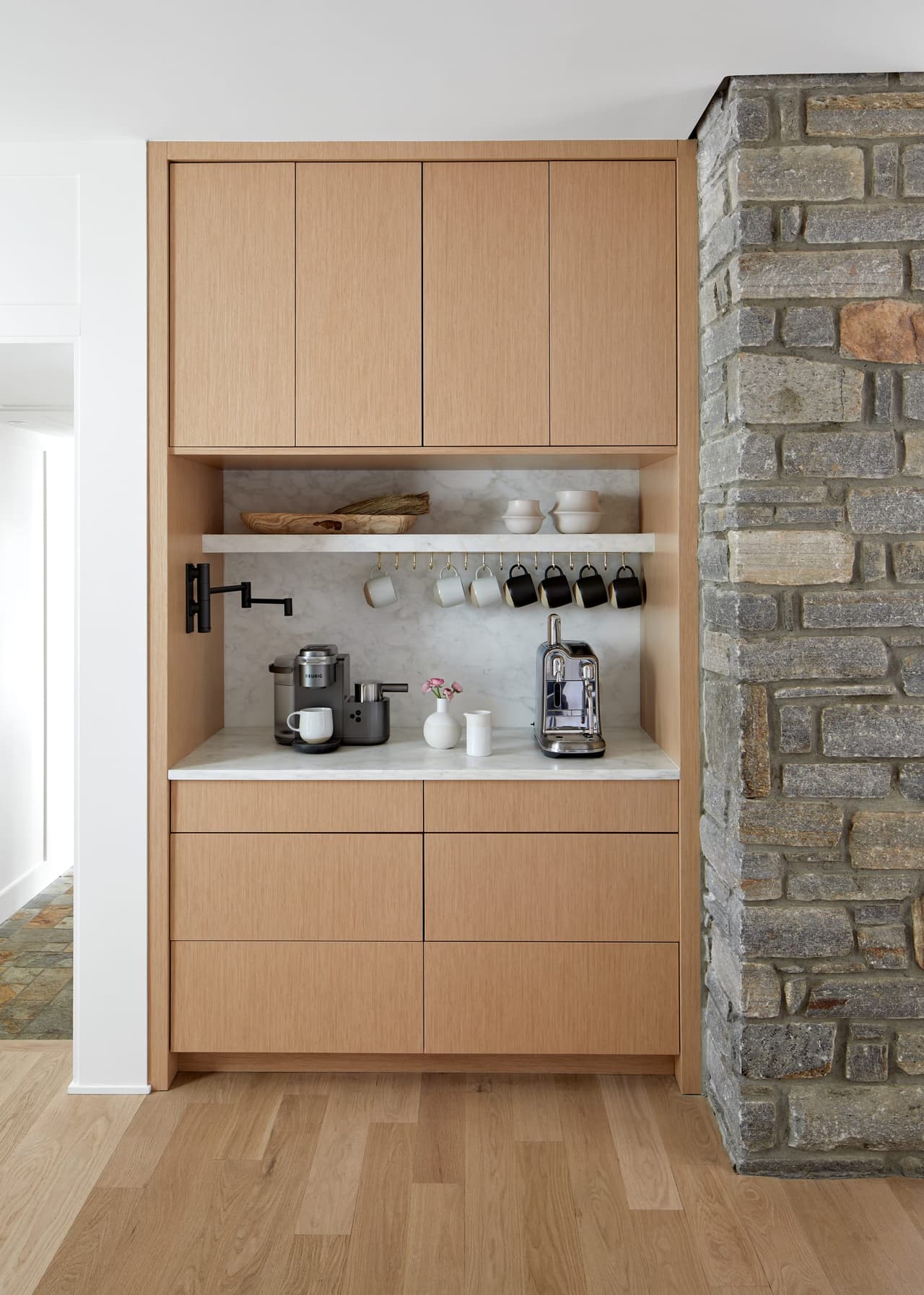 Coffee bar in white oak cabinetry set into a stone wall in a Westfield, NJ kitchen renovation, with open shelving and an espresso machine