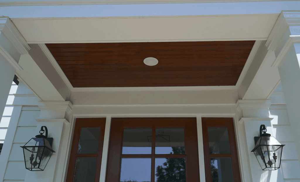 Front entry of a Westfield, NJ remodel and addition, with a stained plank porch ceiling, gas lanterns either side and a wood door between sidelights