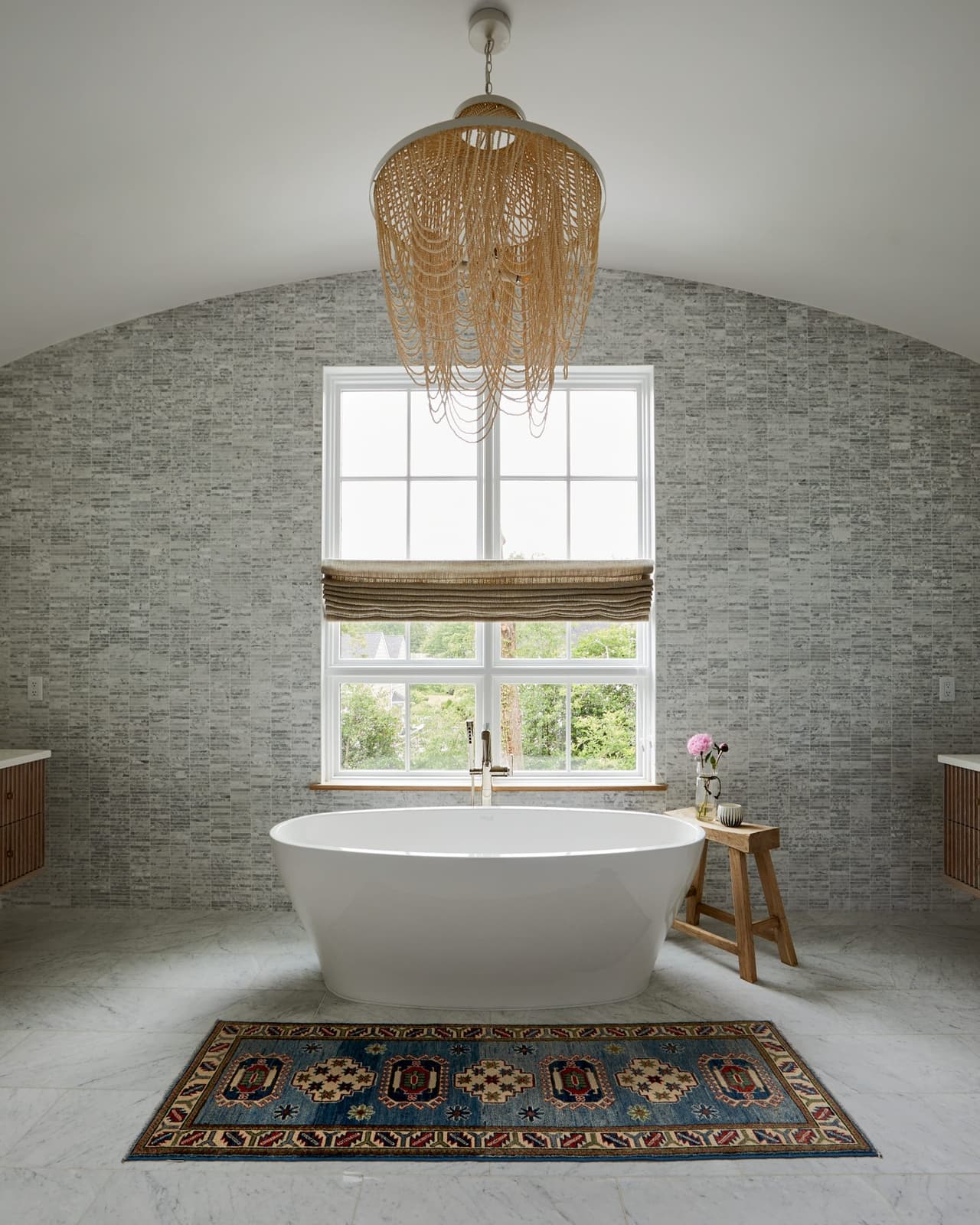 Freestanding tub under a beaded chandelier in the barrel-vaulted, tiled alcove of a Westfield, NJ new home's primary bathroom