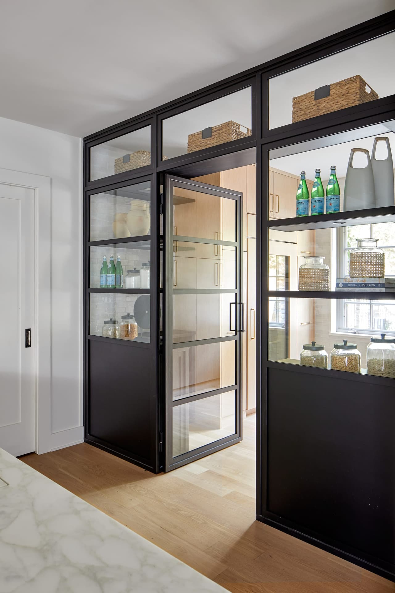 Black steel-framed glass doors standing open on a shelved pantry in a Westfield, NJ kitchen renovation, built by Michael Robert Construction