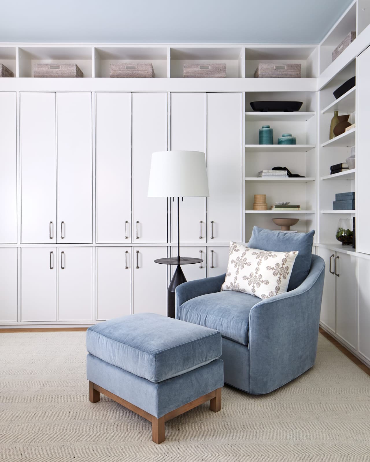 Home office in a Westfield, NJ renovation with floor-to-ceiling white built-ins, open shelving and a blue swivel chair and ottoman