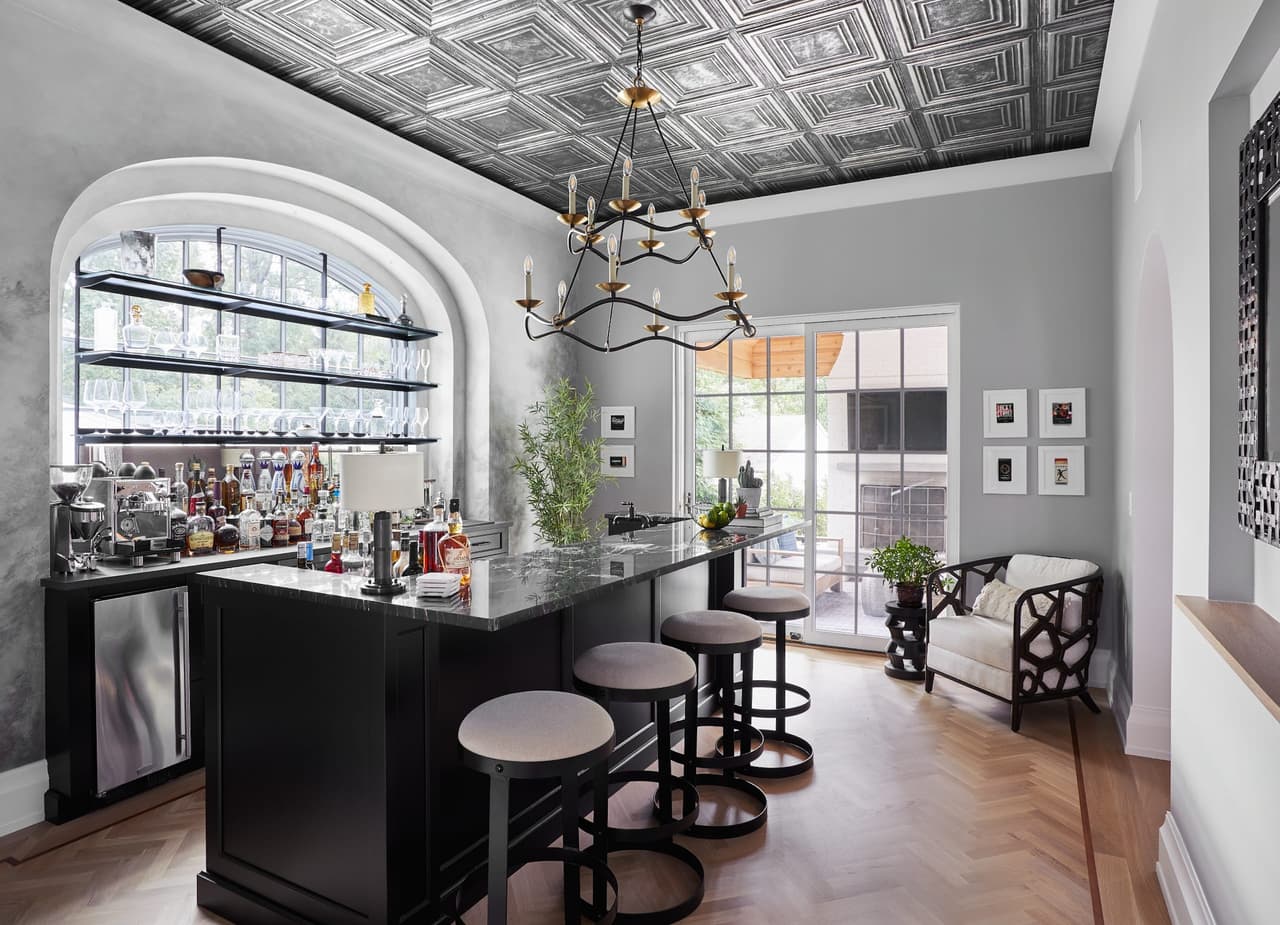 Pub room in a Westfield, NJ new-construction home with a black bar and counter stools, a pressed-tin ceiling and an iron chandelier