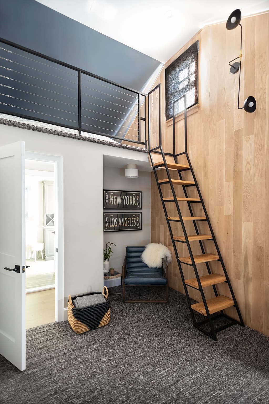 Loft bedroom in a Westfield, NJ remodel, with a ship's ladder up to a sleeping platform behind a black railing and a hanging chair below