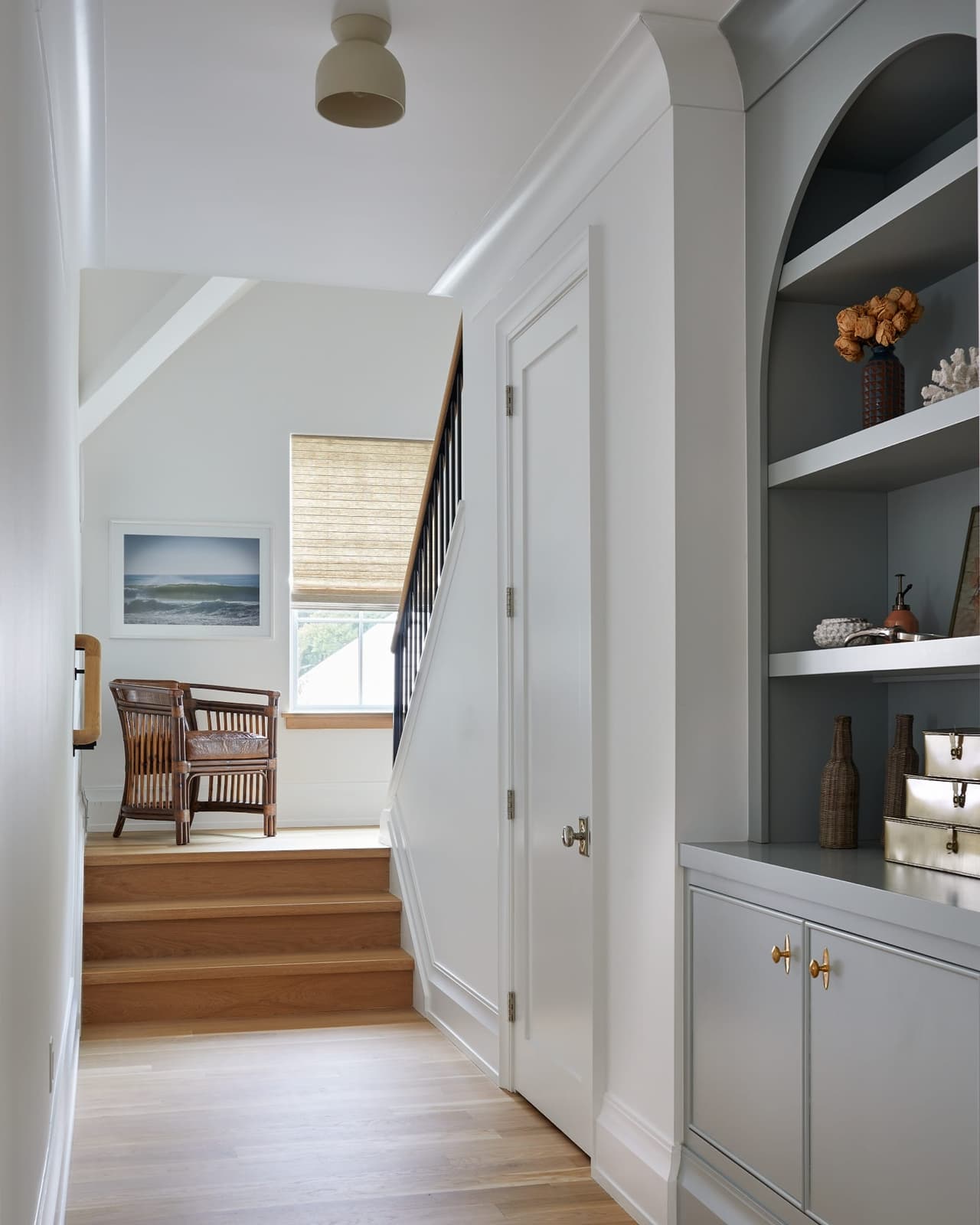 Upstairs hallway of a Westfield, NJ new home with built-in cabinetry, an arched display niche and the stair dropping away to a window on the landing