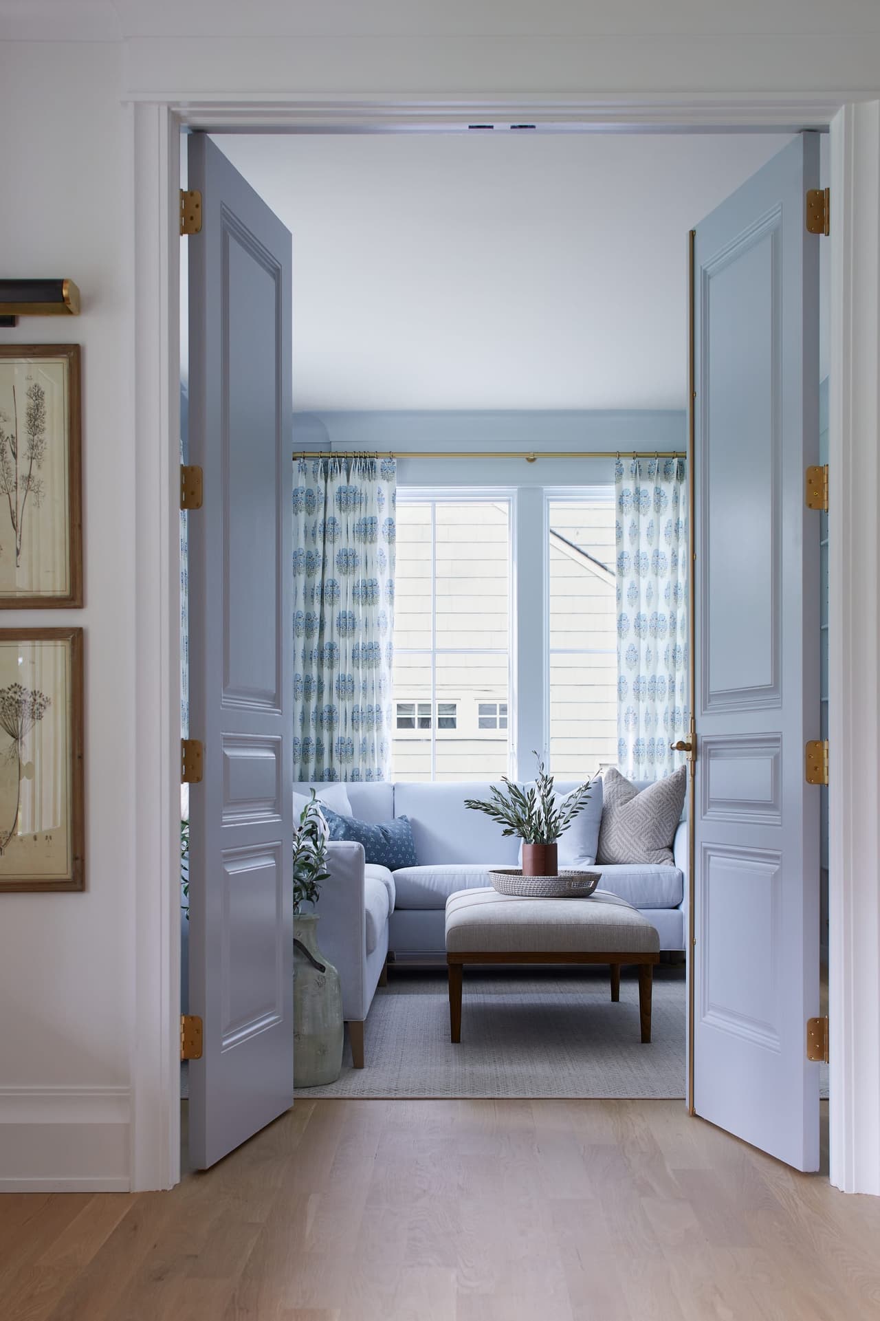 Pair of pale blue paneled doors standing open from the hall into the living room of a Westfield, NJ new-construction home