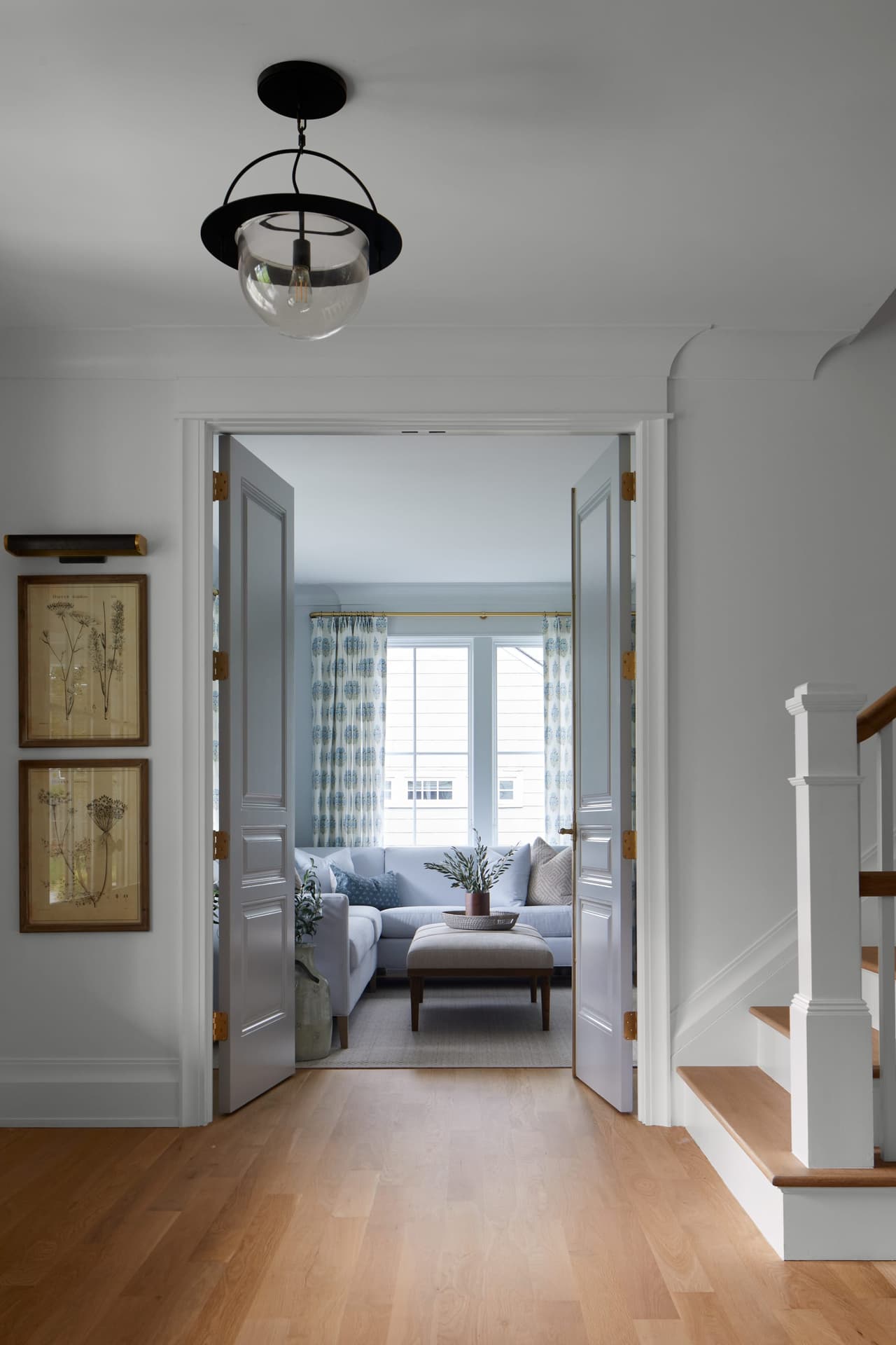 Foyer of a Westfield, NJ new-construction home looking through an open doorway to a sitting room, with a ring lantern overhead and the stair to the right