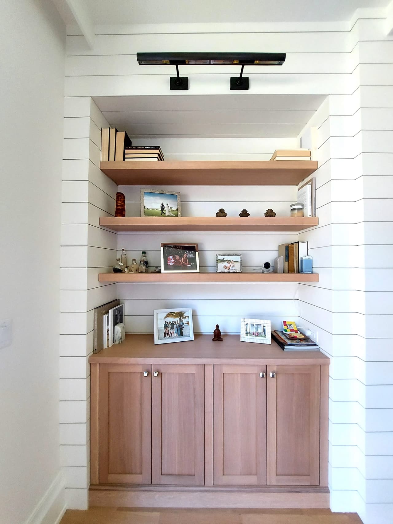 Shiplap built-in with floating oak shelves over wood base cabinets in a Westfield, NJ new-construction home, lit by a track above