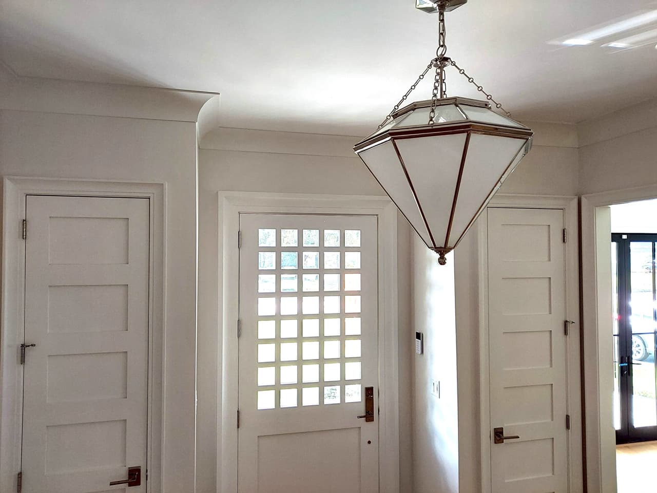 Foyer of a Westfield, NJ new build with a faceted lantern pendant over the entry and a divided-light window in the front door