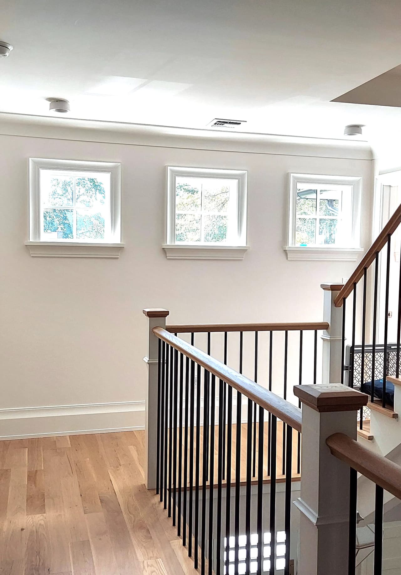 Upstairs hallway of a Westfield, NJ custom new-construction home, with three windows along the wall and an open stair rail of black balusters