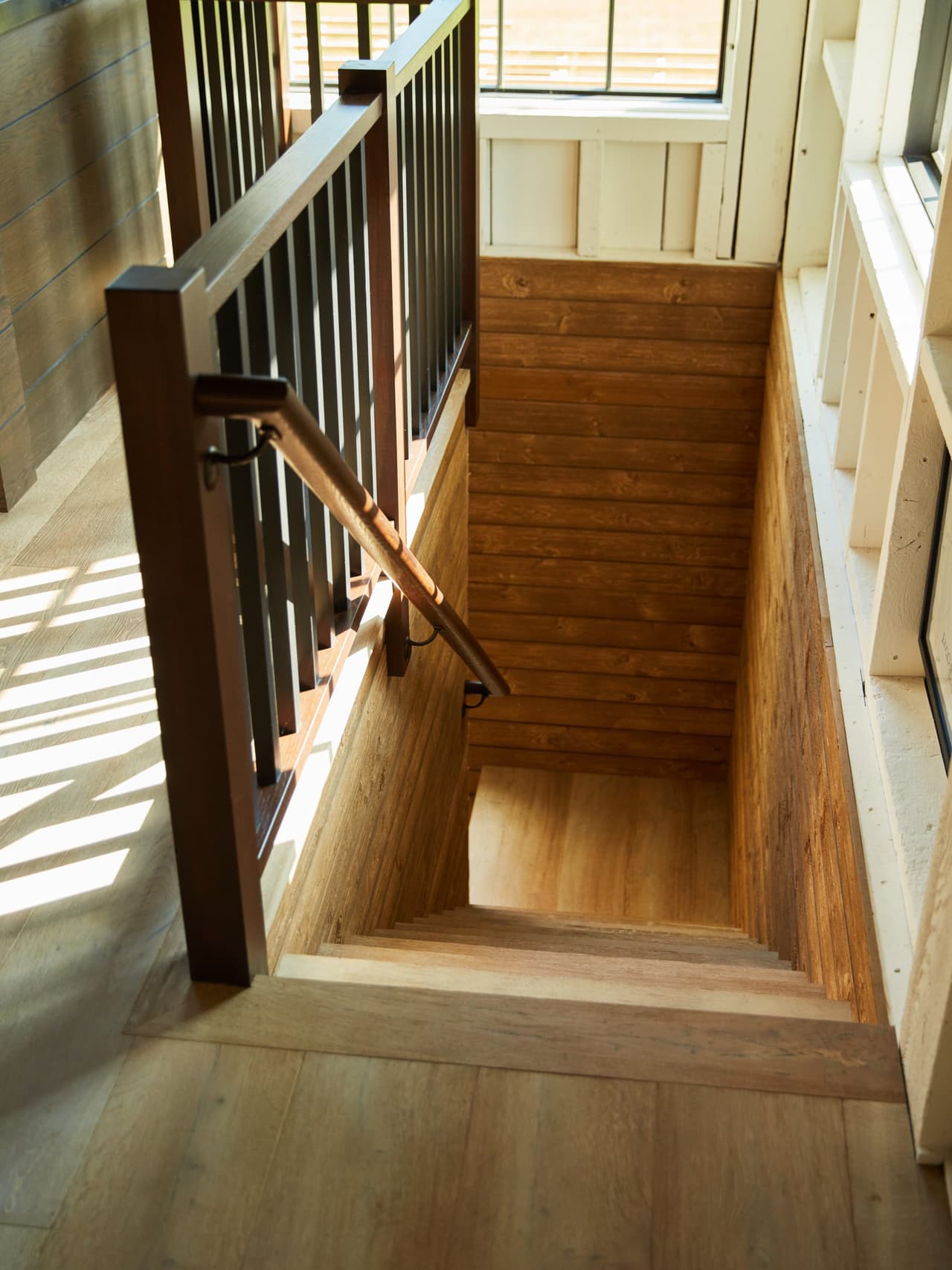 Stair of a Westfield, NJ historic barn renovation seen from above, with wood treads, a wood handrail and black metal balusters