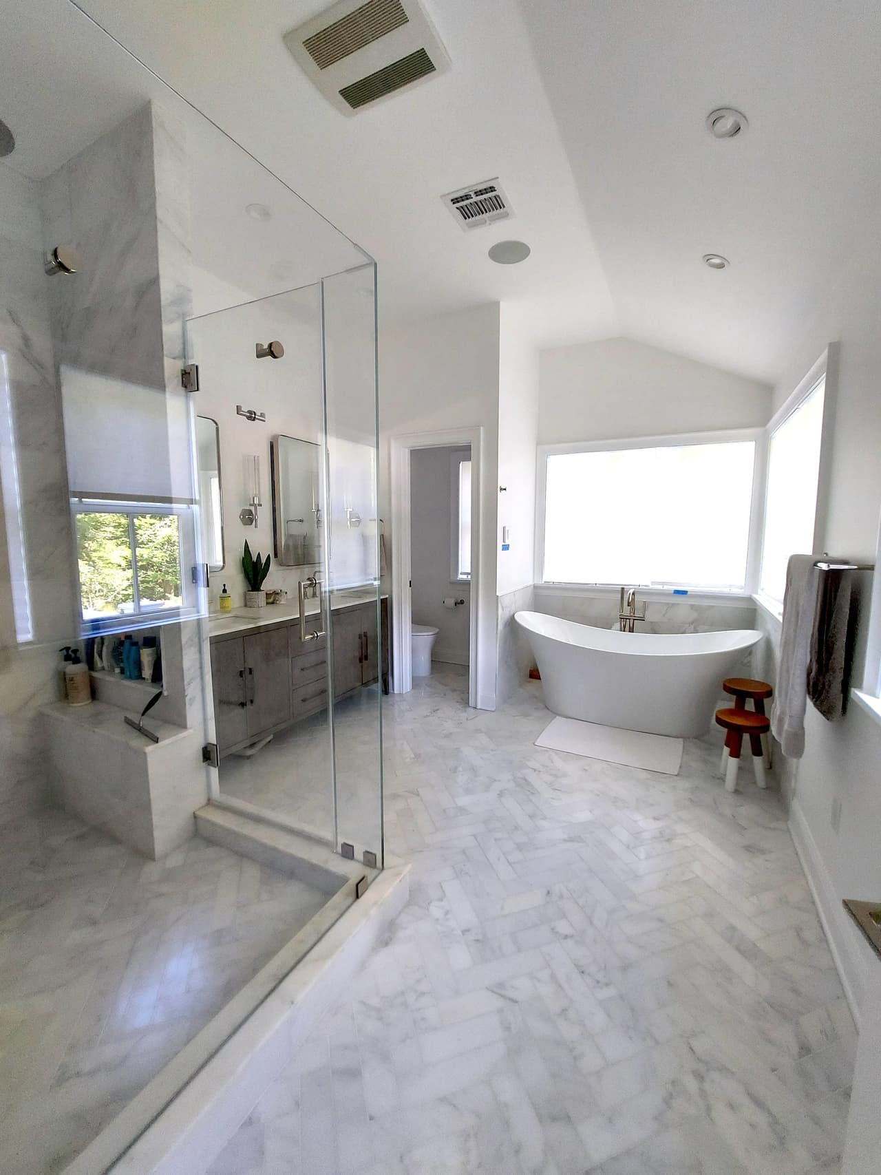 Primary bathroom of a Westfield, NJ new-construction home, with a glass shower, a freestanding tub under the window and a marble tile floor