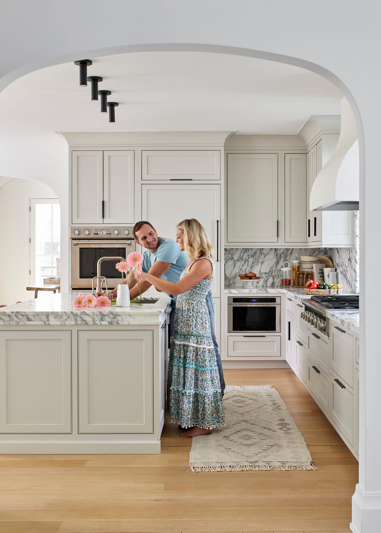 Mike and Ellie Mroz in the kitchen of a Westfield, NJ custom home, beside the marble-topped island under an arched cased opening, built by Michael Robert Construction