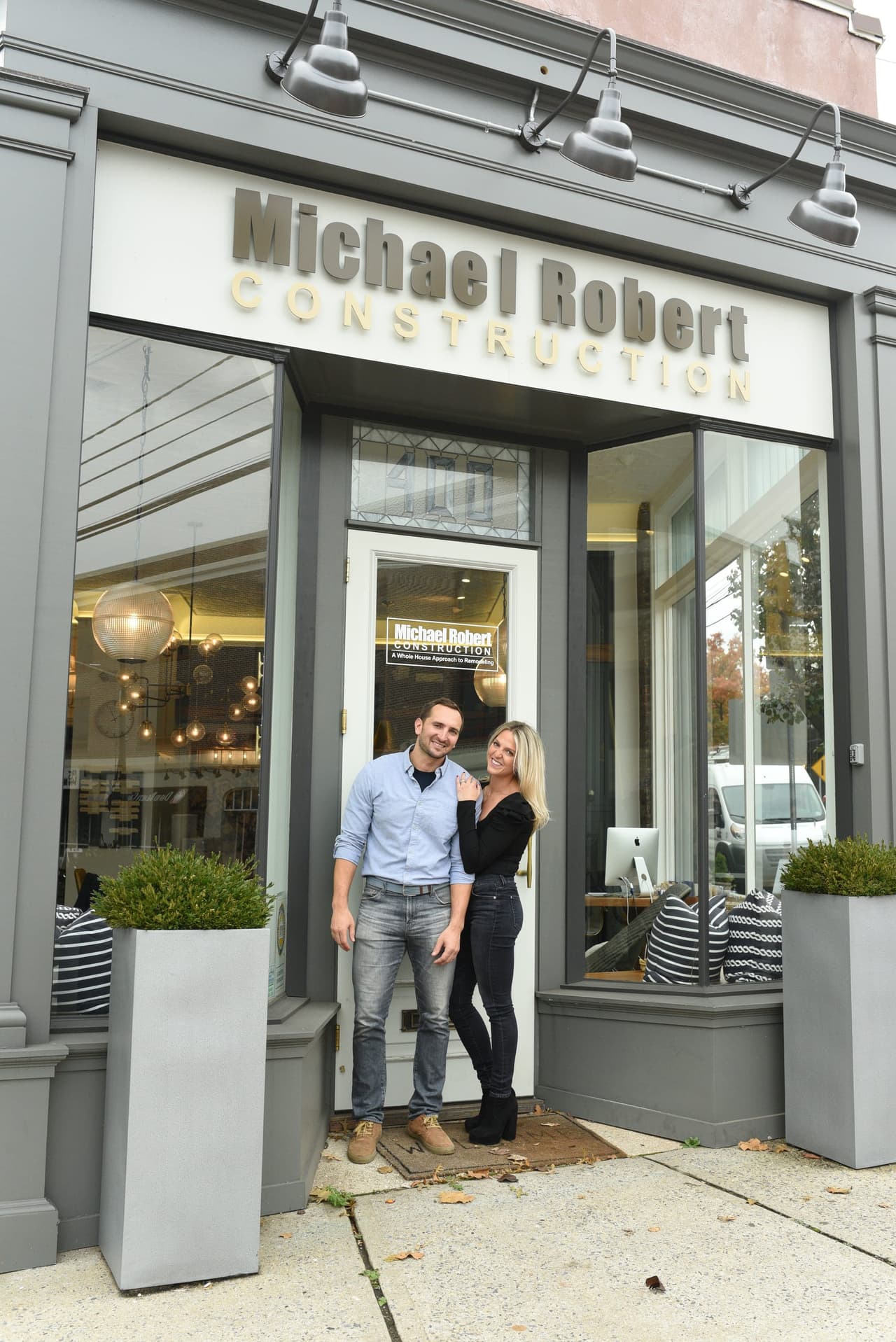 Mike and Ellie Mroz outside the Michael Robert Construction office on West Broad Street in Westfield, NJ, under the storefront sign