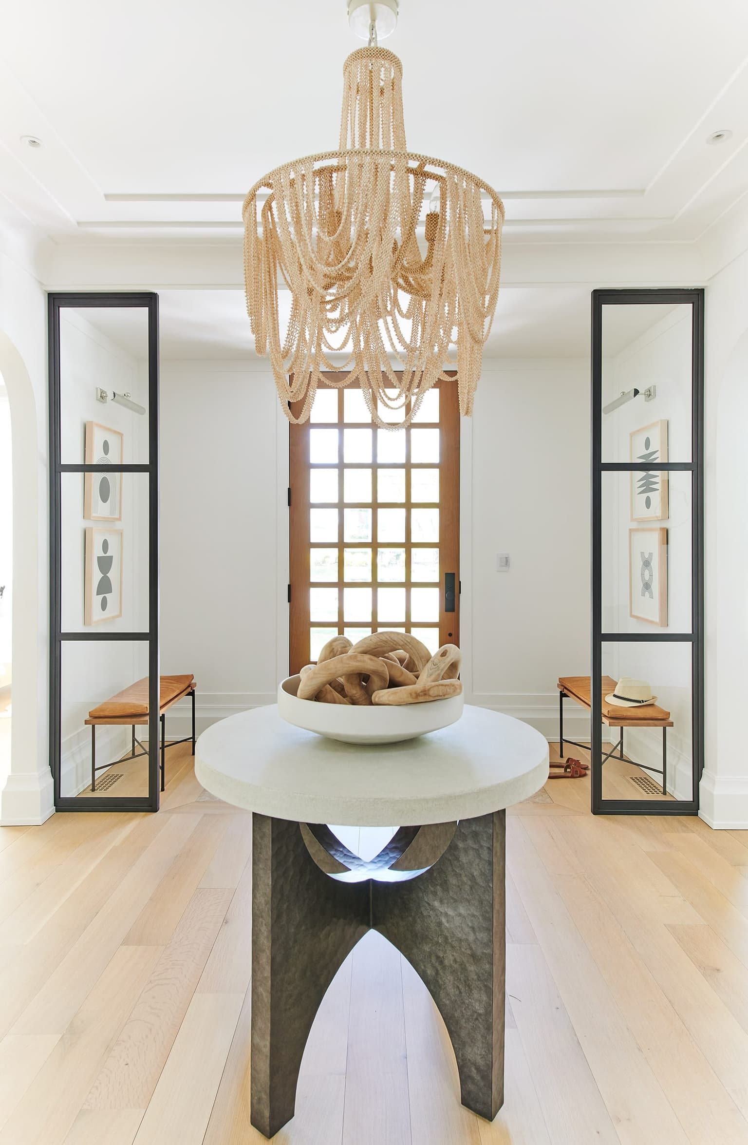 Dining area of the Mroz family home in Westfield, NJ, with a stone pedestal table under a beaded chandelier between two steel-framed mirrors
