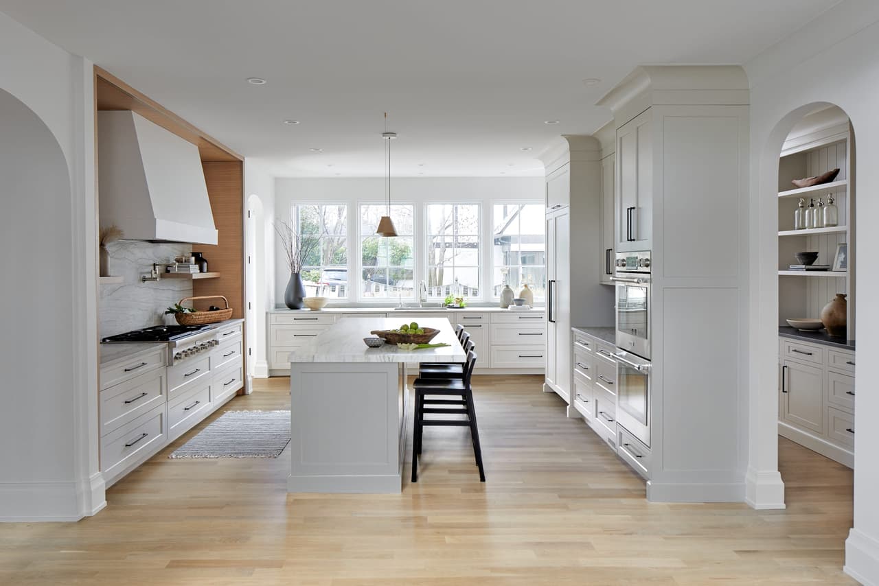 Custom kitchen in a Westfield, NJ home addition and renovation, seen the length of the room past the plaster hood to the island and the windows beyond, built by Michael Robert Construction