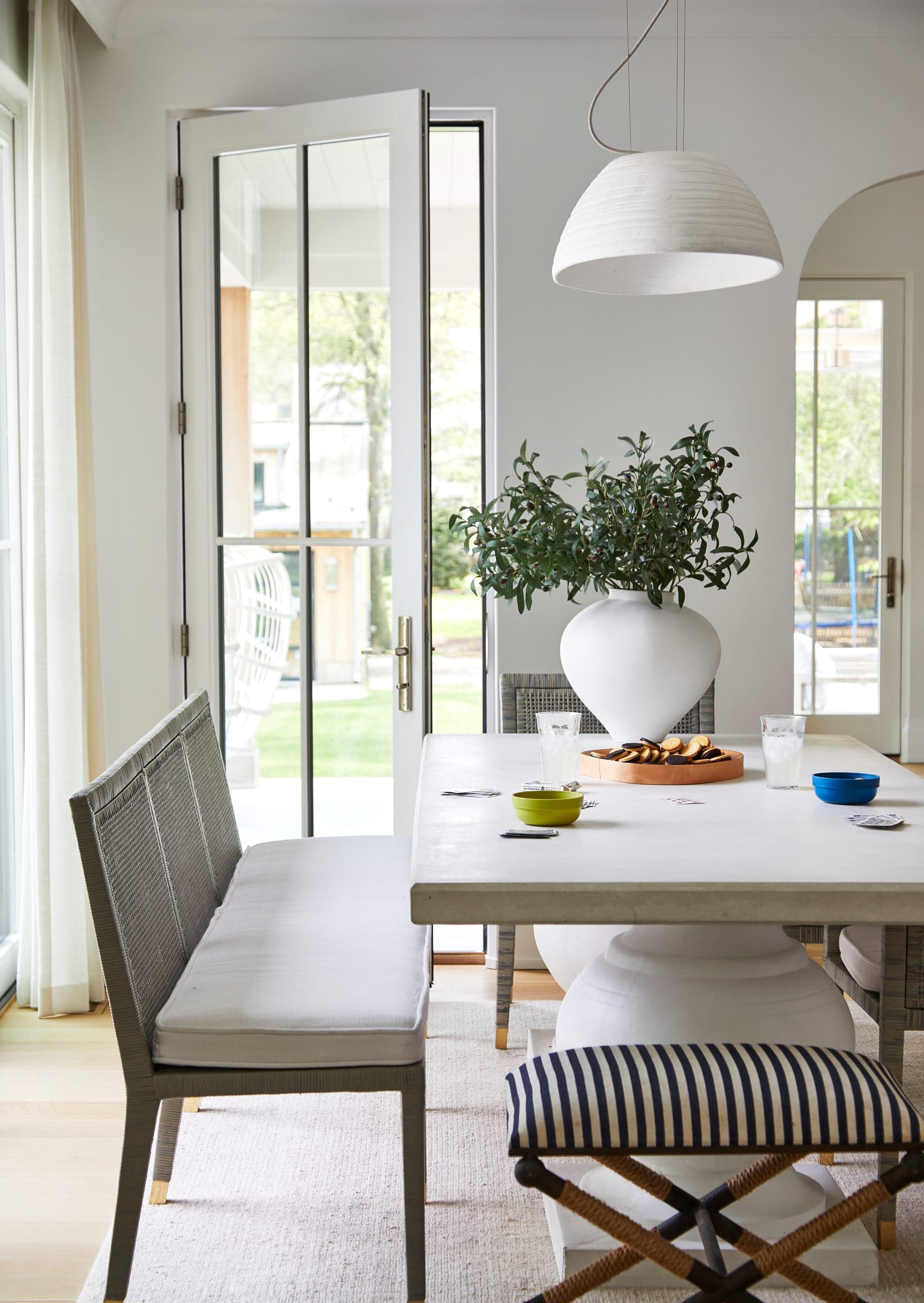Dining area off the kitchen of a Westfield, NJ new home, with dome pendants over the table and French doors open to the garden on two sides