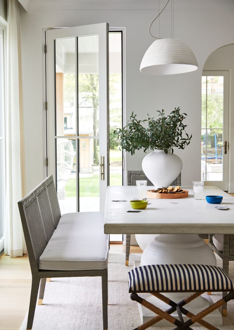 Dining area off the kitchen of a Westfield, NJ new home, with dome pendants over the table and French doors open to the garden on two sides