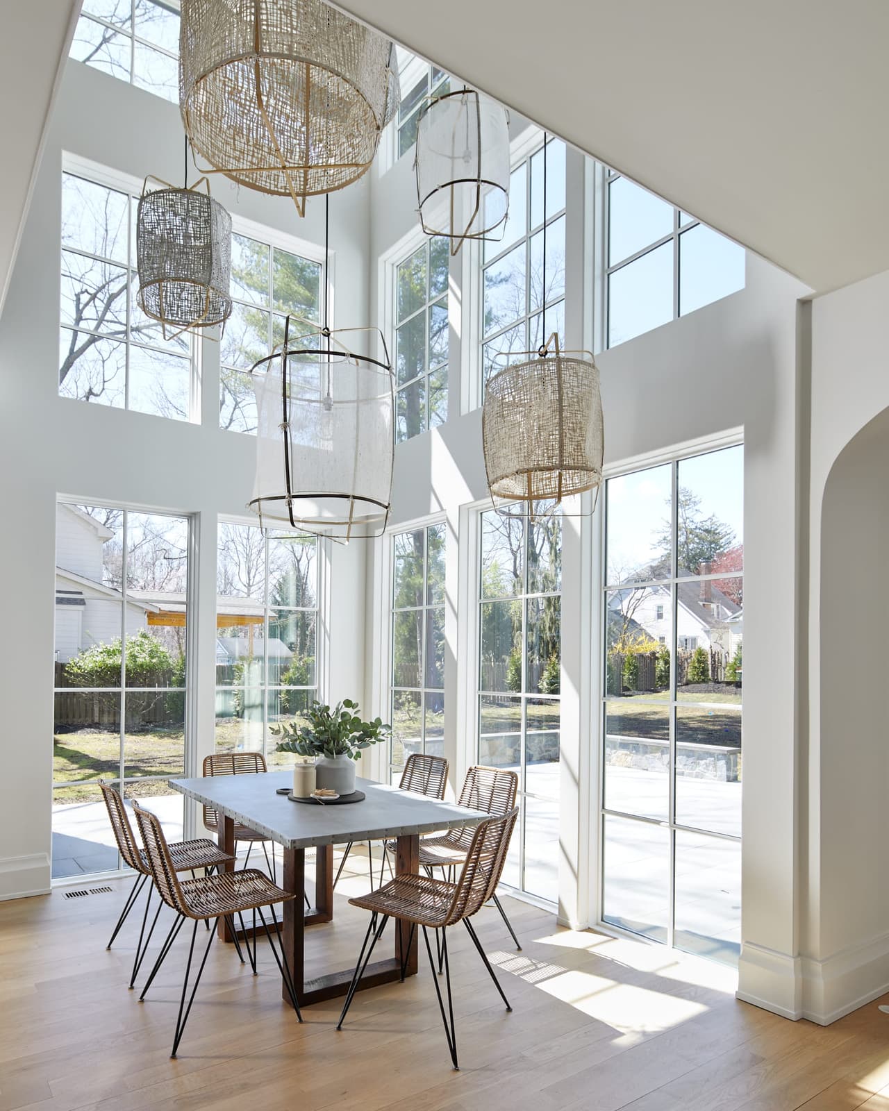 Double-height breakfast nook in a Westfield, NJ renovation and addition, with two storeys of glass, woven pendants and a round table in the corner