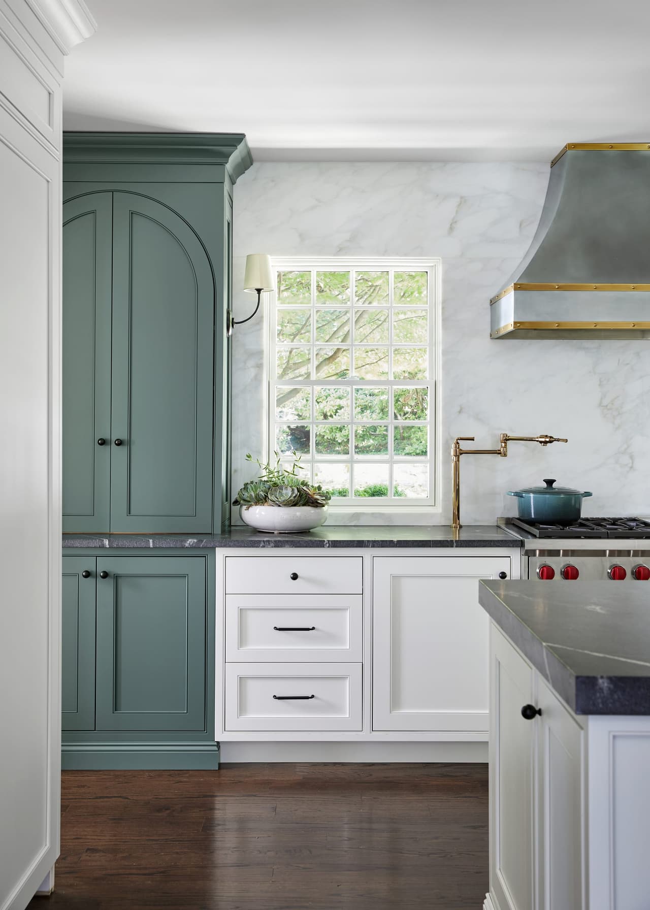 Arched green pantry cabinetry beside a brass-trimmed plaster hood and white inset cabinets in a Westfield, NJ kitchen renovation