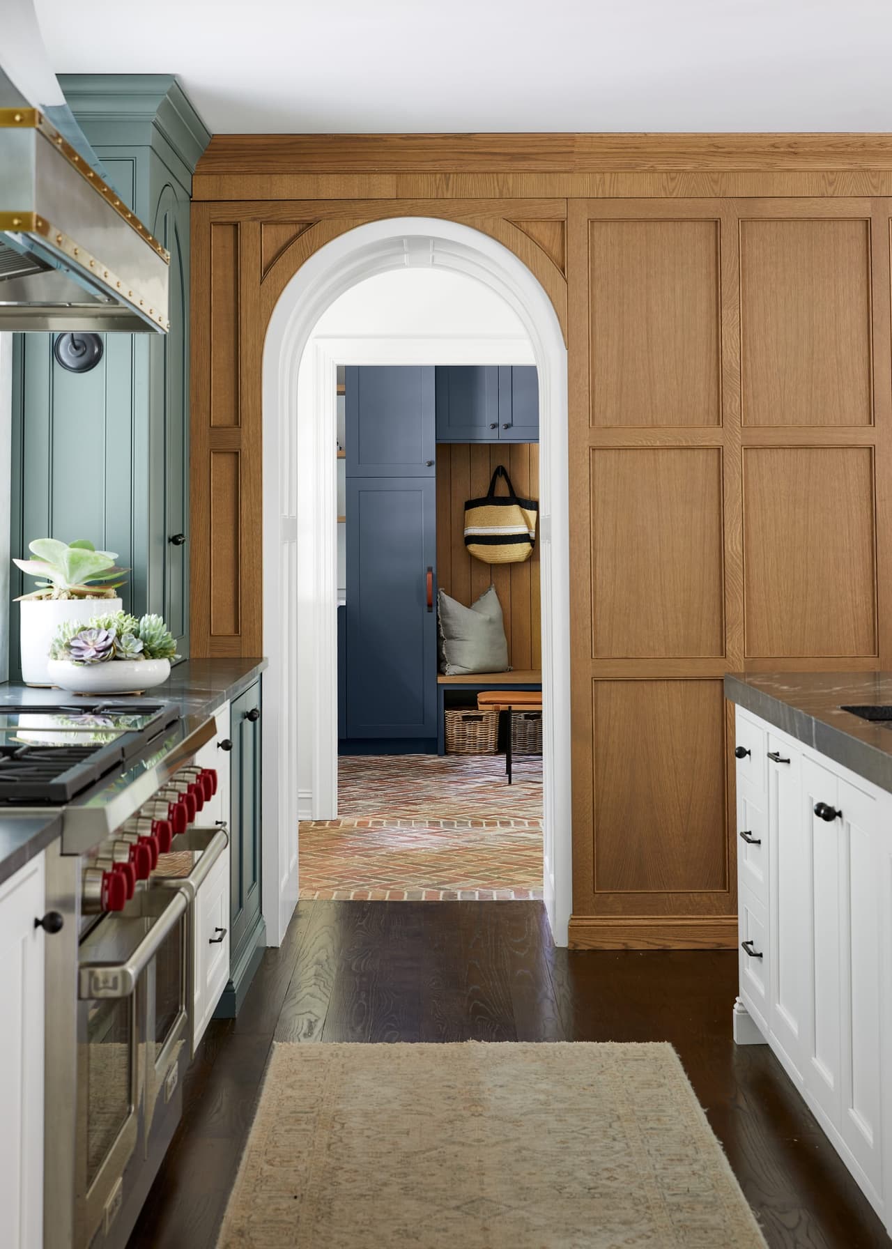 Arched doorway set into white oak paneling between the kitchen and the hall of a Westfield, NJ kitchen renovation, with the range and counter in the foreground