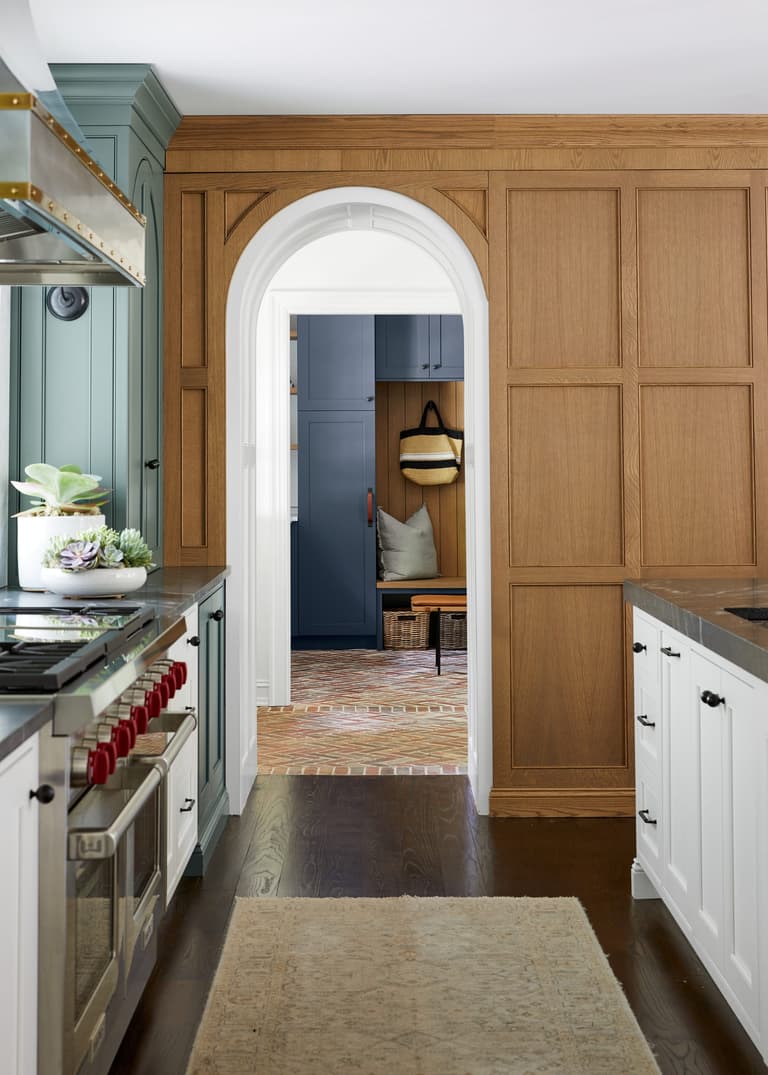 Arched doorway set into white oak paneling between the kitchen and the hall of a Westfield, NJ kitchen renovation, with the range and counter in the foreground