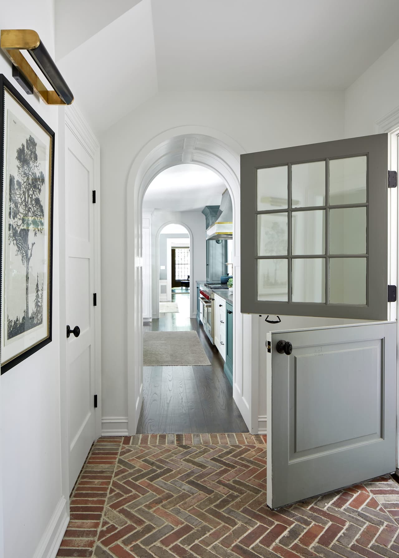 Dutch door standing open onto a herringbone brick floor in the entry of a Westfield, NJ home renovation, looking through an arched opening