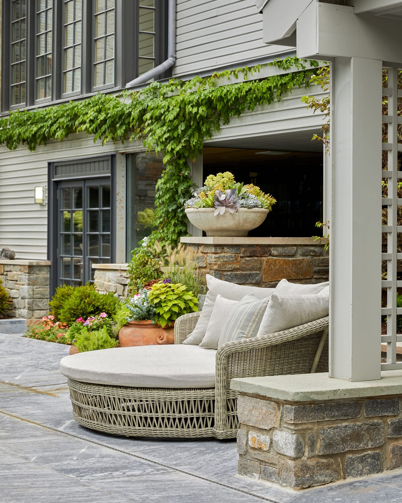 Double lounge seating under a vine-covered pergola beside a stone planter in a Westfield, NJ backyard